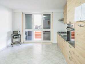 Eine Küche mit einer Mikrowelle auf einem Wagen, einem Herd und einer Schiebetür zu einem Balkon.