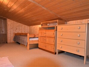 Ein Schlafzimmer mit einem Etagenbett, einer Holzkommode und Teppichboden.