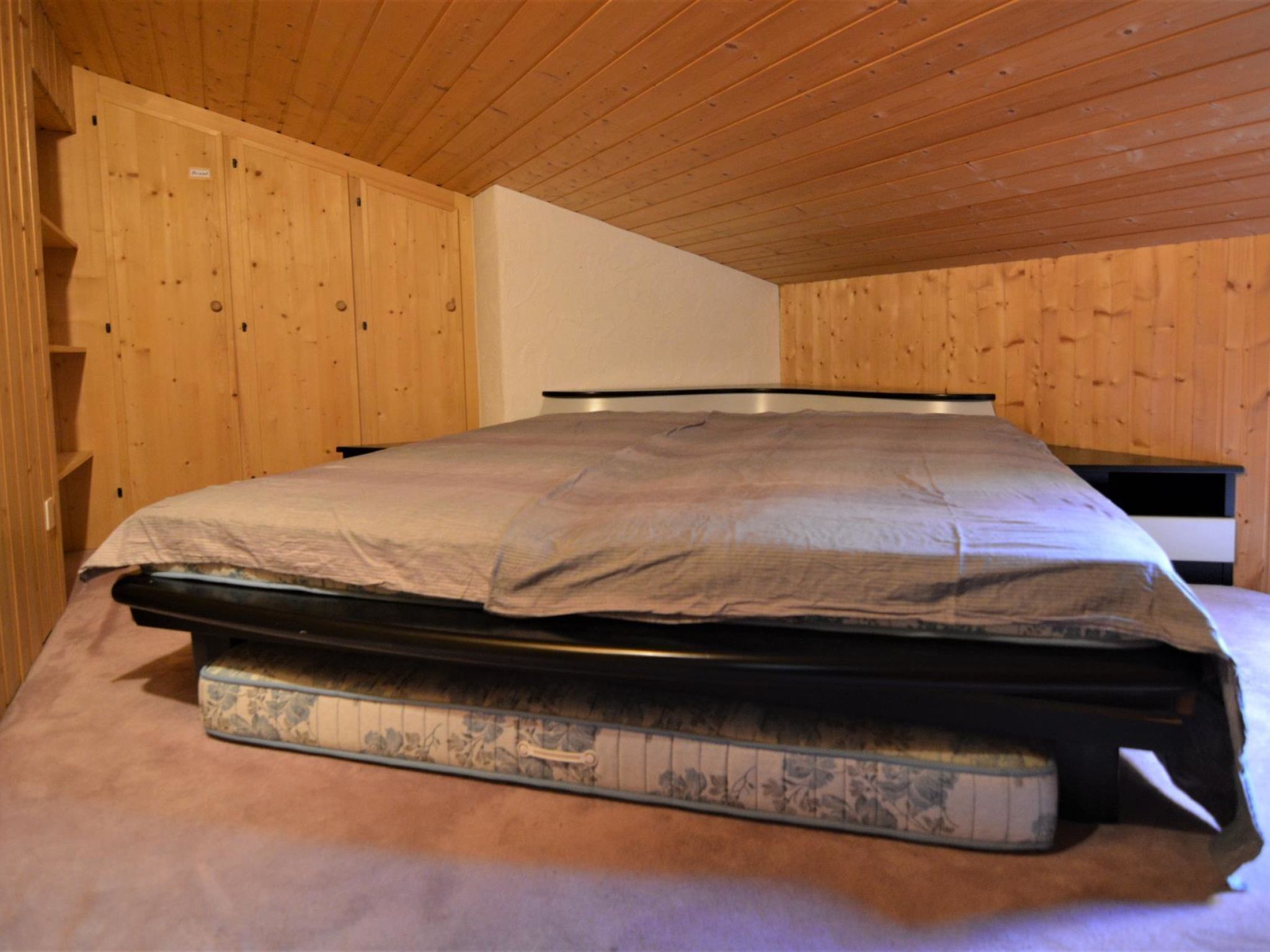 Une pièce avec un lit, des murs en bois et un plafond en pente.
