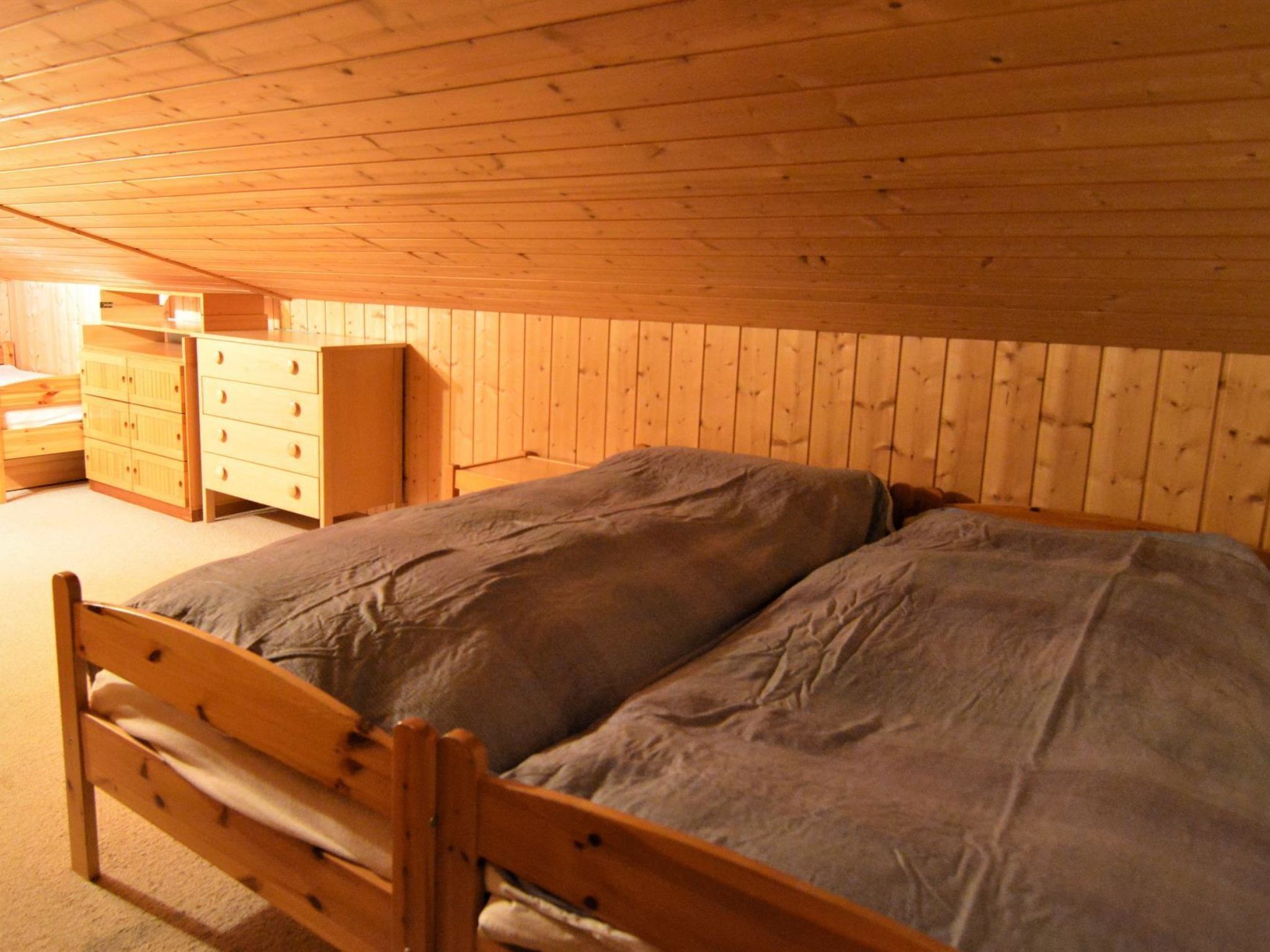 A bedroom with a wooden bed, a dresser, and a nightstand.
