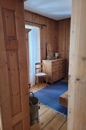 A wooden room with a chair, a dresser, and a mirror. - Roccabella Appartement/Fewo, Dusche oder Bad, WC, 2 Schlafräume by Interhome (Bivio)