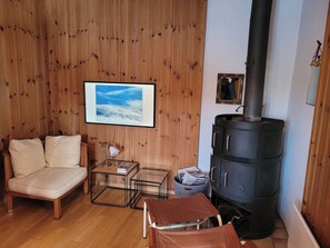 Ein gemütliches Wohnzimmer mit einer Couch, einem kleinen Tisch, einer Lampe, einem gerahmten Bild und einer Holzvertäfelung.