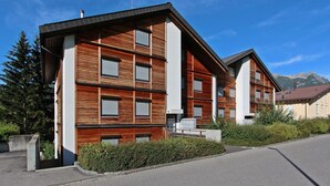 Ein modernes, mehrgeschossiges Gebäude mit Holzfassade und großen Fenstern.