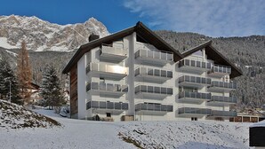 Ein mehrstöckiges Hotel mit Balkonen vor einer verschneiten Bergkulisse.
