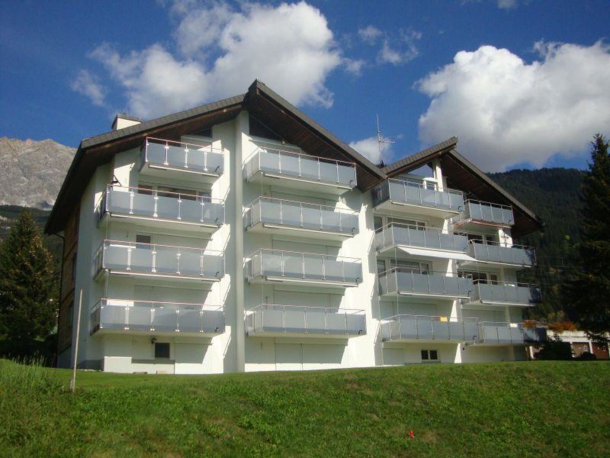 Un hôtel à plusieurs étages, doté de balcons, situé dans un cadre montagneux.
