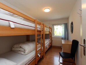 Une chambre avec deux lits superposés, un bureau et une chaise.