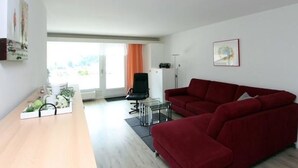 Ein modernes Wohnzimmer mit einem Holztisch, einem roten Sofa und einem schwarzen Sessel.