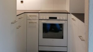 A compact kitchen with white cabinets, a built-in oven, and a countertop. - Casa Surselva Whg Bilger Appartement/Fewo, Bad, WC, 2 Schlafräume by Interhome (Savognin)