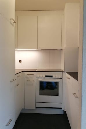 A compact kitchen with white cabinets, a built-in oven, and a countertop. - Casa Surselva Whg Bilger Appartement/Fewo, Bad, WC, 2 Schlafräume by Interhome (Savognin)