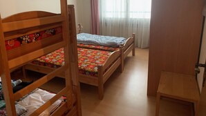 A room with two wooden bunk beds, a small table, a window with sheer curtains, and a painting on the wall. - Casa Surselva Whg Bilger Appartement/Fewo, Bad, WC, 2 Schlafräume by Interhome (Savognin)