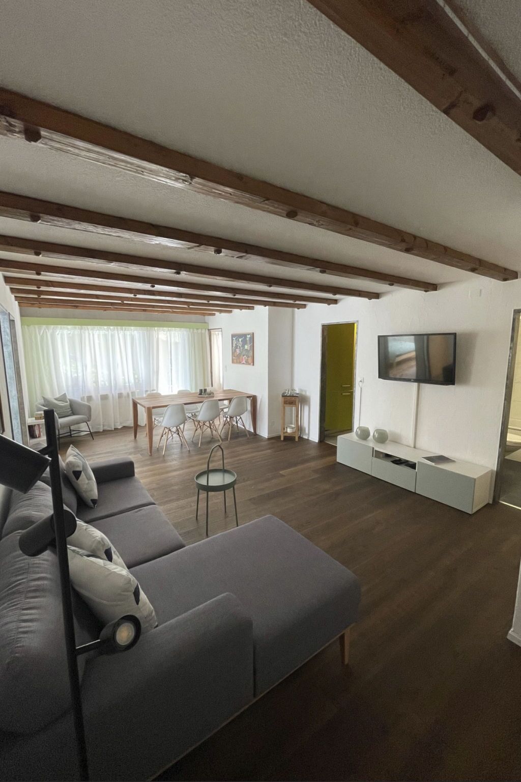 A modern living room with a sofa, a dining table, and a TV.