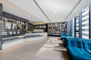A modern library with bookshelves, seating areas, and large windows. - Noodle Nest..  Central Rama 9 - Comfortable Stay near MRT (Krung Thep Maha Nakhon)