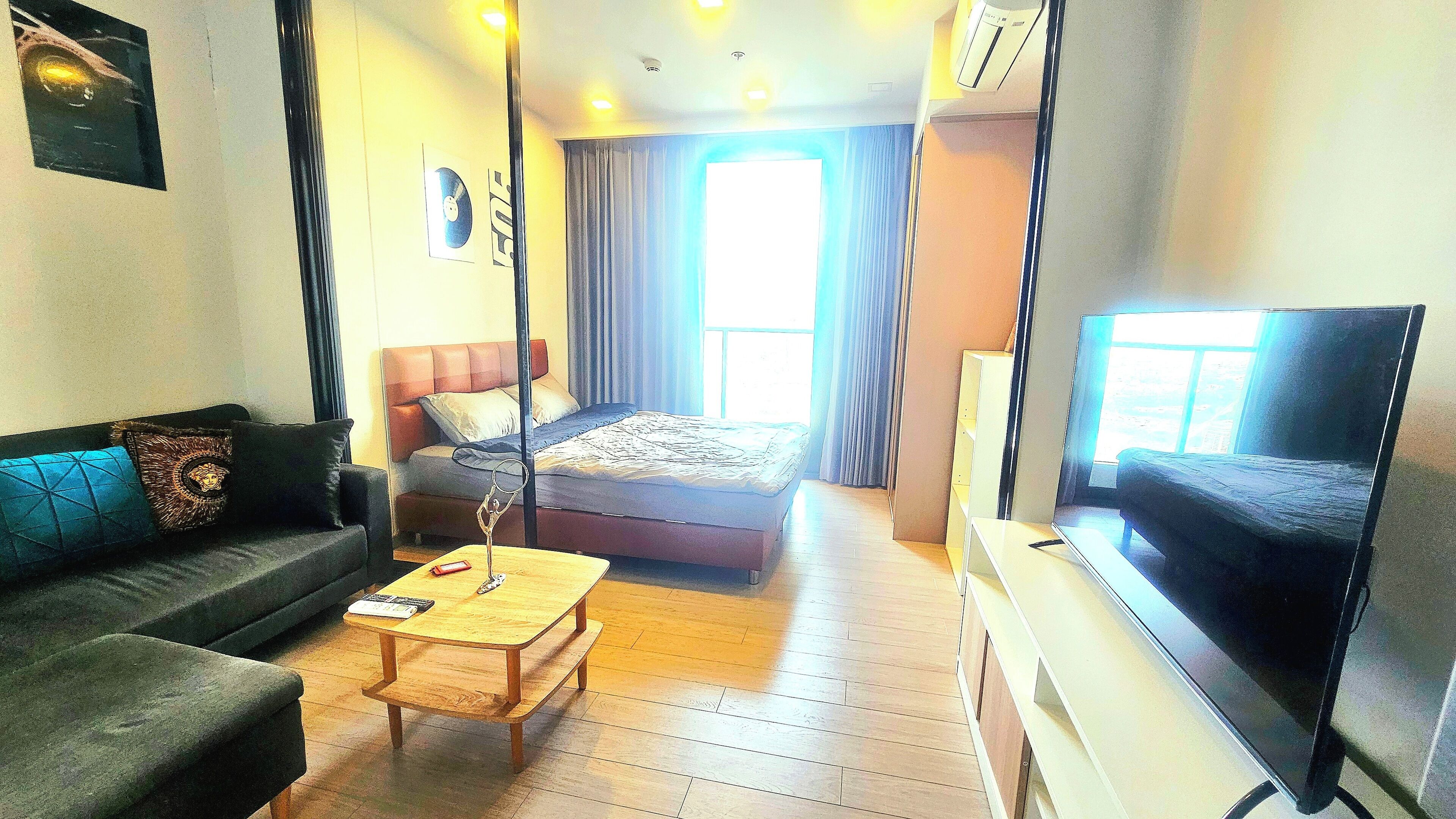 A compact hotel room with a bed, a sofa, a TV, and a small table.