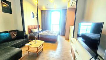 A compact hotel room with a bed, a sofa, a TV, and a small table.