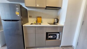 A compact kitchen with a built-in refrigerator, a microwave, and a sink. - Noodle Nest..  Central Rama 9 - Comfortable Stay near MRT (Krung Thep Maha Nakhon)