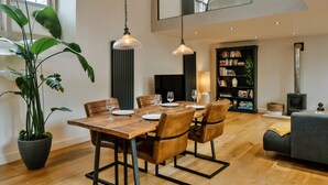A dining area with a wooden table, leather chairs, and hanging pendant lights. - Heather View Chapel (Bradwell)