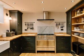 A modern kitchen with dark cabinetry, a stainless steel stove, and a marble backsplash. - Heather View Chapel (Bradwell)