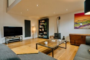 A modern living room with a flat-screen TV, a bookshelf, a fireplace, and a painting on the wall. - Heather View Chapel (Bradwell)