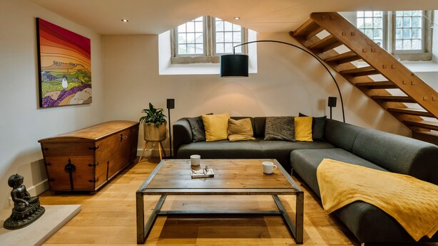 A modern living room with a sofa, a wooden coffee table, a Buddha statue, and a painting on the wall. - Heather View Chapel (Bradwell)
