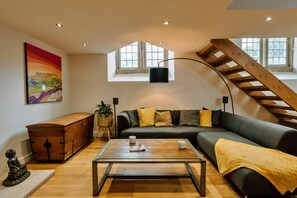 Ein modernes Wohnzimmer mit einer Couch, einem Holztisch, einer Buddha-Statue und einem Bild an der Wand.