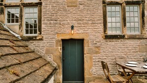 A stone building with a dark green door, a stone staircase, and a wooden table with plates and cutlery. - Heather View Chapel (Bradwell)