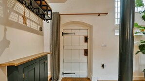 A hallway with a wooden bench, a door with a black handle, and a window with a plant. - Heather View Chapel (Bradwell)