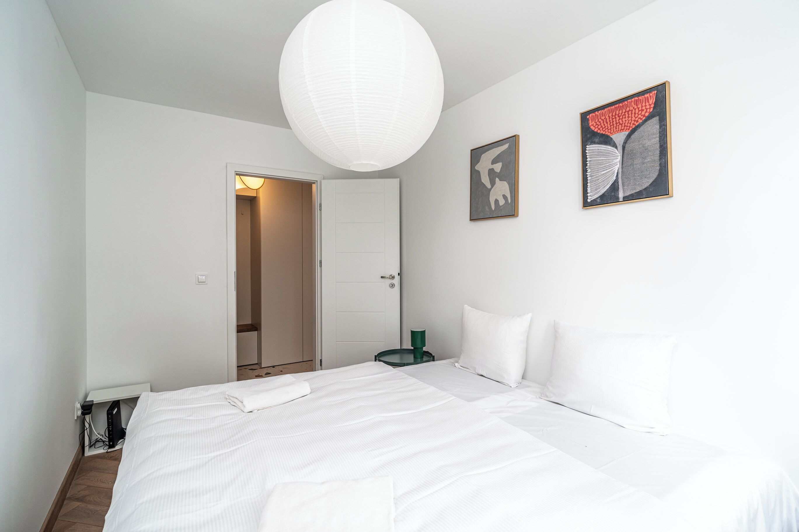 Un dormitorio con cama, una puerta, una obra de arte colgada en la pared y una lámpara en el techo.