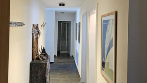 Um corredor com um banco de madeira, decorações fixadas na parede e quadros emoldurados.