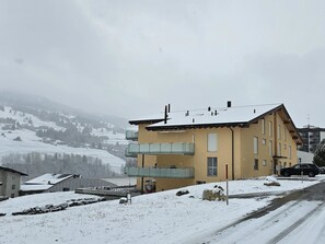 Ein mehrstöckiges Gebäude mit Balkonen, eine verschneite Landschaft und eine Straße im Vordergrund.