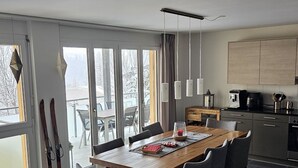 Uma cozinha moderna com área de jantar, grandes janelas e vista para uma paisagem nevada.