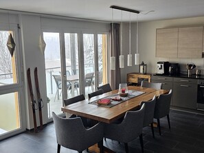 Eine moderne Küche mit Essbereich, großen Fenstern und Blick auf eine verschneite Landschaft.