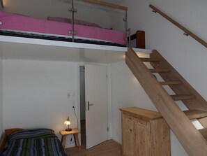 A room with a bunk bed, a wooden ladder, a desk with a lamp, and a wardrobe. - Casa Stella Appartement/Fewo, Dusche, WC, 2 Schlafräume by Interhome (Savognin)