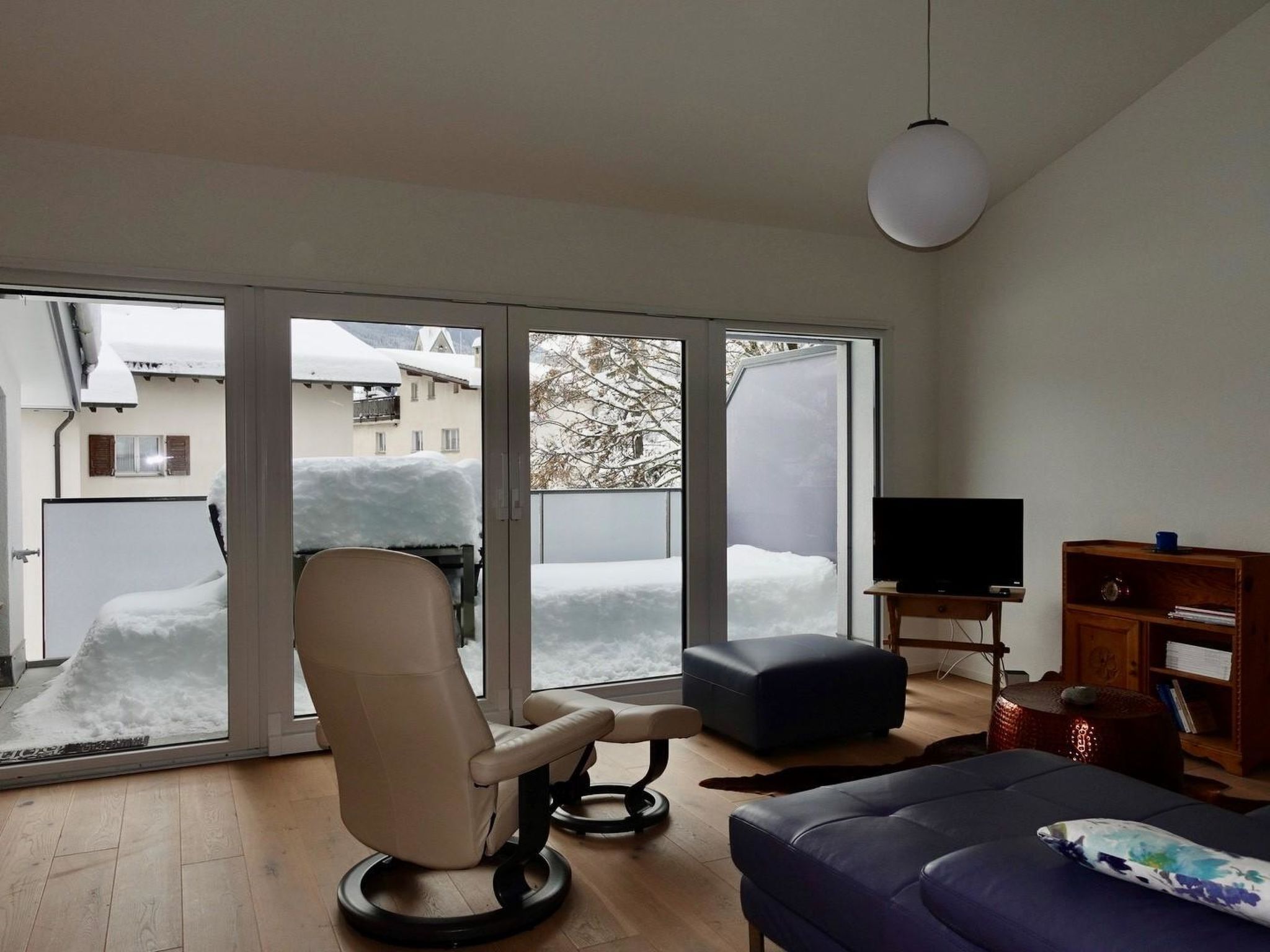 Una sala de estar con un sofá, una silla, un televisor y una estantería.
