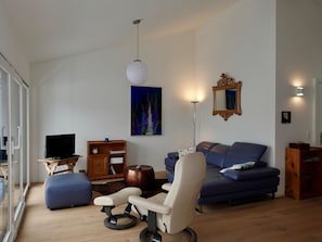 A modern living room with a sofa, a chair, a television, and a painting on the wall. - Casa Stella Appartement/Fewo, Dusche, WC, 2 Schlafräume by Interhome (Savognin)