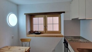 A compact kitchen with a dining table, chairs, a window, and modern appliances. - Haus Rizzi Appartement/Fewo, Dusche, WC, 1 Schlafraum by Interhome (Bivio)