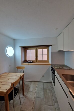 A compact kitchen with a dining table, chairs, a window, and modern appliances. - Haus Rizzi Appartement/Fewo, Dusche, WC, 1 Schlafraum by Interhome (Bivio)