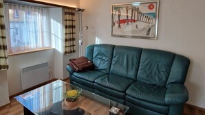 A living room with a green sofa, a glass coffee table, and a painting on the wall. - Haus Rizzi Appartement/Fewo, Dusche, WC, 1 Schlafraum by Interhome (Bivio)