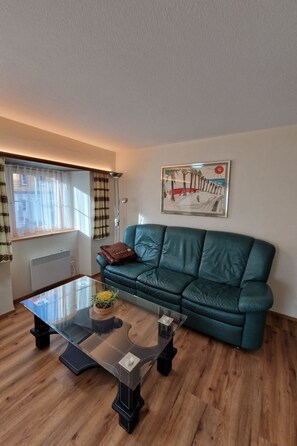 A living room with a green sofa, a glass coffee table, and a painting on the wall. - Haus Rizzi Appartement/Fewo, Dusche, WC, 1 Schlafraum by Interhome (Bivio)