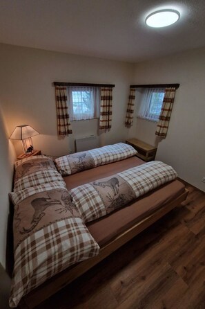 A bedroom with a bed, a bedside table, a lamp, and a window with curtains. - Haus Rizzi Appartement/Fewo, Dusche, WC, 1 Schlafraum by Interhome (Bivio)