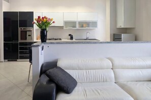 A modern kitchen with a built-in oven, a coffee machine, and a vase with flowers on the counter. - An elegant and welcoming 80-square-meter apartment, perfect for three people, located on the raised ground floor of an upscale building.The property is ideally situated for exploring the city: the Royal Villa of Monza is just a 10-minute walk away, while (Monza)