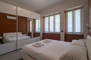 A modern hotel room with a large bed, a mirror, and a window. - An elegant and welcoming 80-square-meter apartment, perfect for three people, located on the raised ground floor of an upscale building.The property is ideally situated for exploring the city: the Royal Villa of Monza is just a 10-minute walk away, while (Monza)