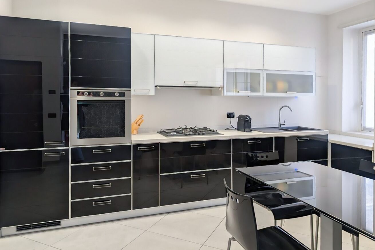 A modern kitchen with black and white cabinetry, a gas stove, and a sink.