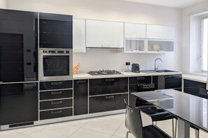 A modern kitchen with black and white cabinetry, a gas stove, and a sink. - An elegant and welcoming 80-square-meter apartment, perfect for three people, located on the raised ground floor of an upscale building.The property is ideally situated for exploring the city: the Royal Villa of Monza is just a 10-minute walk away, while (Monza)