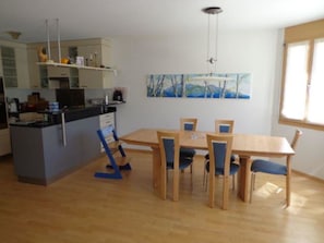 A modern kitchen with a dining area, wooden furniture, and a painting on the wall. - Sot Spondas 15 Appartement/Fewo, Bad, WC, 2 Schlafräume by Interhome (Savognin)