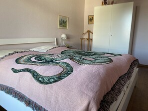 Ein Schlafzimmer mit einem Bett, einem Kleiderschrank, einer Lampe und einem Wandbild.