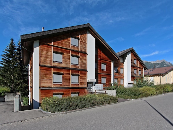 A modern multi-story building with a wooden facade and large windows.