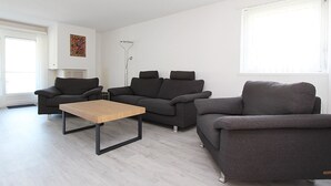 A modern living room with two sofas, a coffee table, and a floor lamp. - Tgesa La Niva 1 Appartement/Fewo, Dusche oder Bad, WC, 2 Schlafräume by Interhome (Savognin)