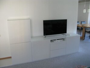 Eine weiße Unterhaltungsanlage mit Fernseher, einer kleinen Ablage und einer Schublade.