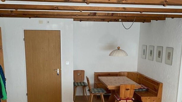 A room with a wooden ceiling, a green sofa, a dining table with chairs, and a door. - Gelgia Sommer-Salis Appartement/Fewo, Bad, WC, 2 Schlafräume by Interhome (Bivio)