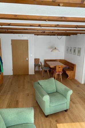 A room with a wooden ceiling, a green sofa, a dining table with chairs, and a door. - Gelgia Sommer-Salis Appartement/Fewo, Bad, WC, 2 Schlafräume by Interhome (Bivio)